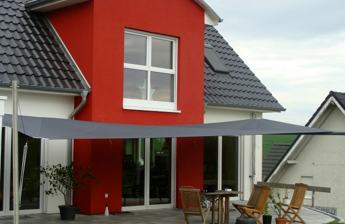 Sonnensegel - elektrisch - in Westfalen in anthrazit vor rot-weißem Haus